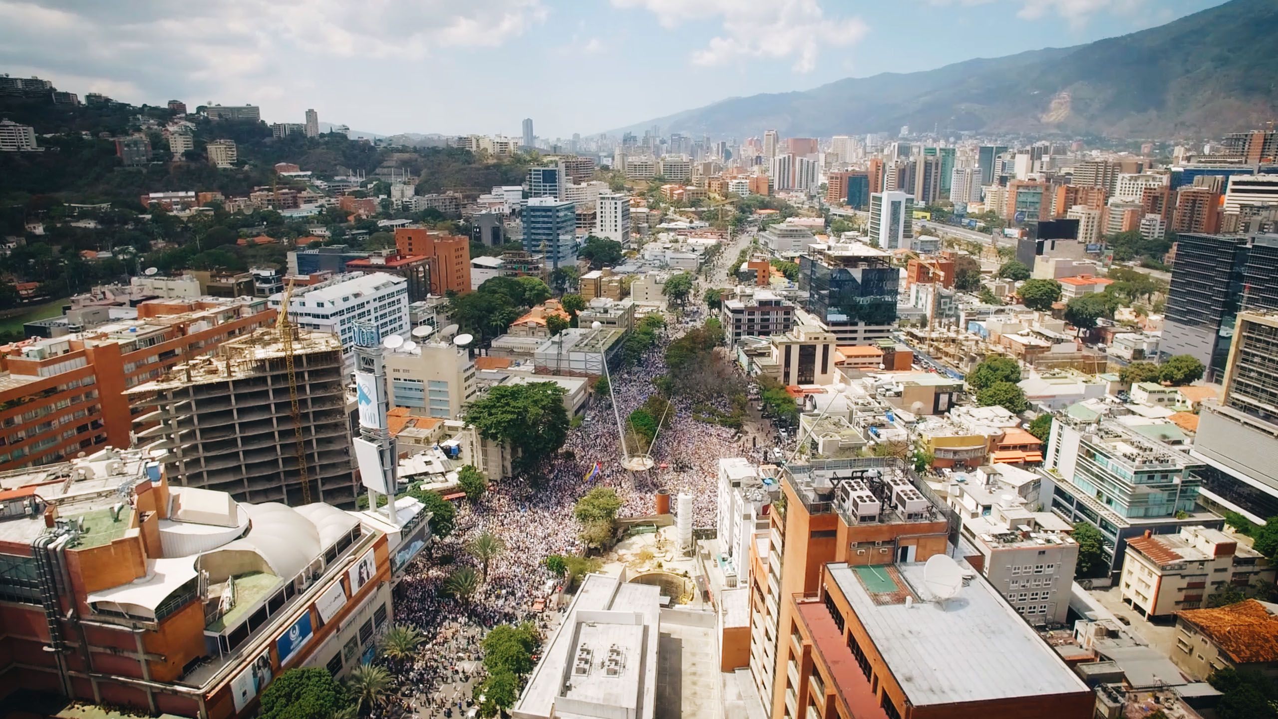 Eine Luftaufnahme eines riesigen Protestmarsches in Caracas, Venezuela, die das Ausmaß der demokratischen Bewegung verdeutlicht, die in der Dokumentation „Women Leading Protests“ thematisiert wird.
