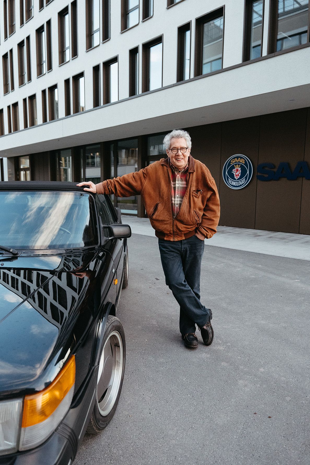The film's lead actor posing with his classic Saab convertible in front of the modern Saab Technologies headquarters during the Visionary Berlin film shoot.