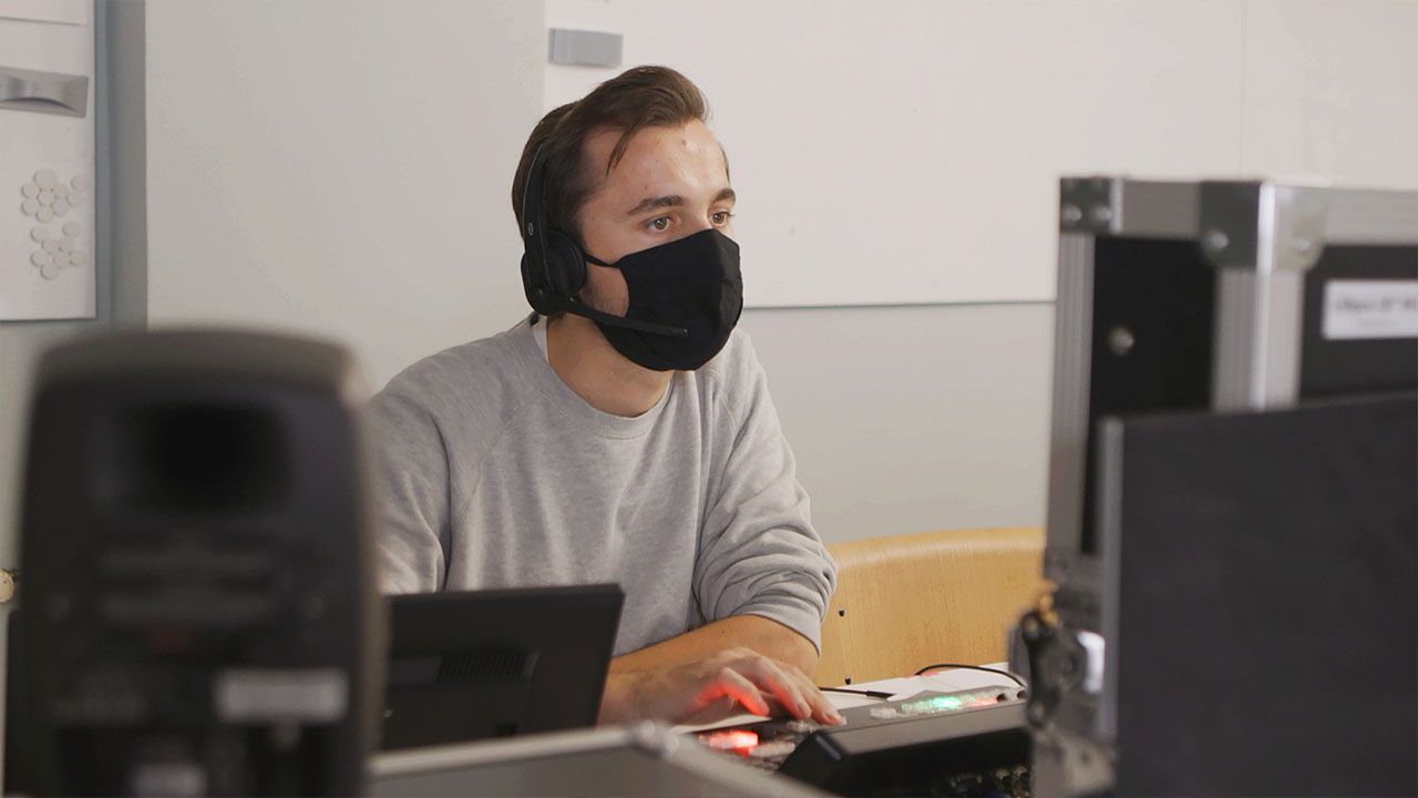 A focused technical director from the Visionary Berlin team managing the live broadcast and audio mix for the Huawei Rebels event from the control station.