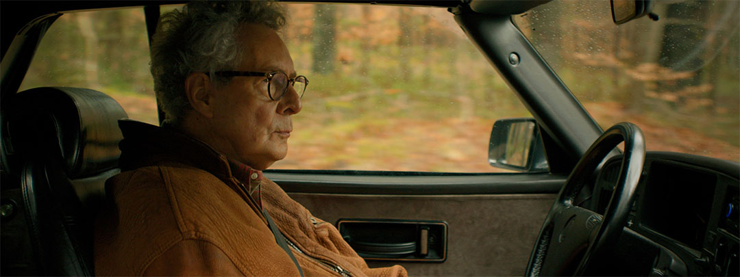 Screenshot: man sitting in a Saab oldtimer