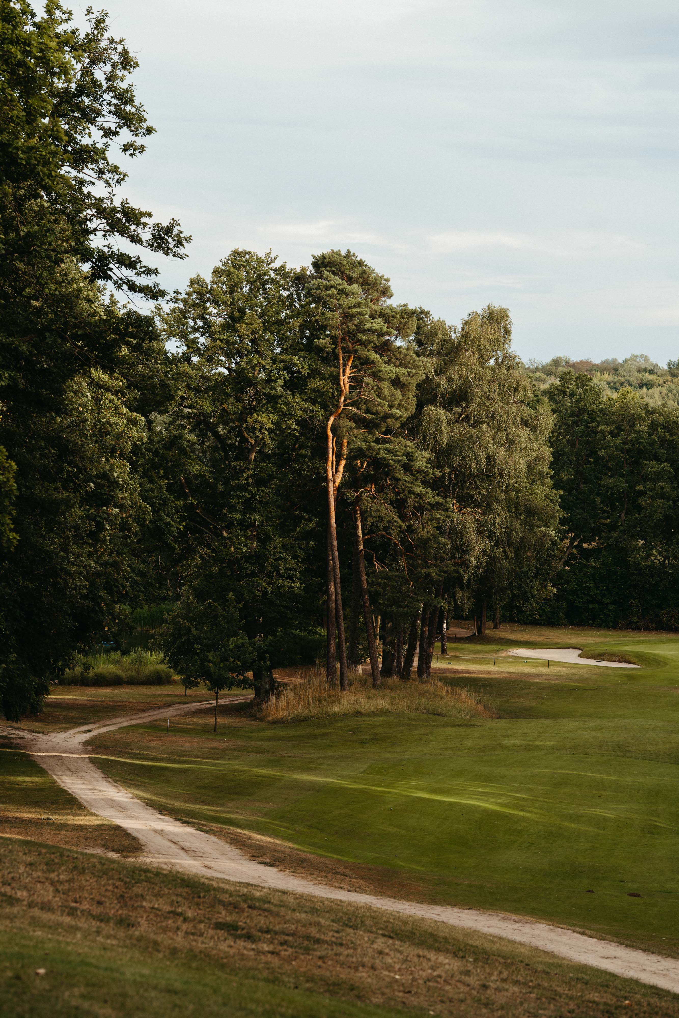 A beautiful landscape shot of a serene golf course, setting the atmospheric backdrop for the Laura Kowohl x Röhnisch brand photography campaign.