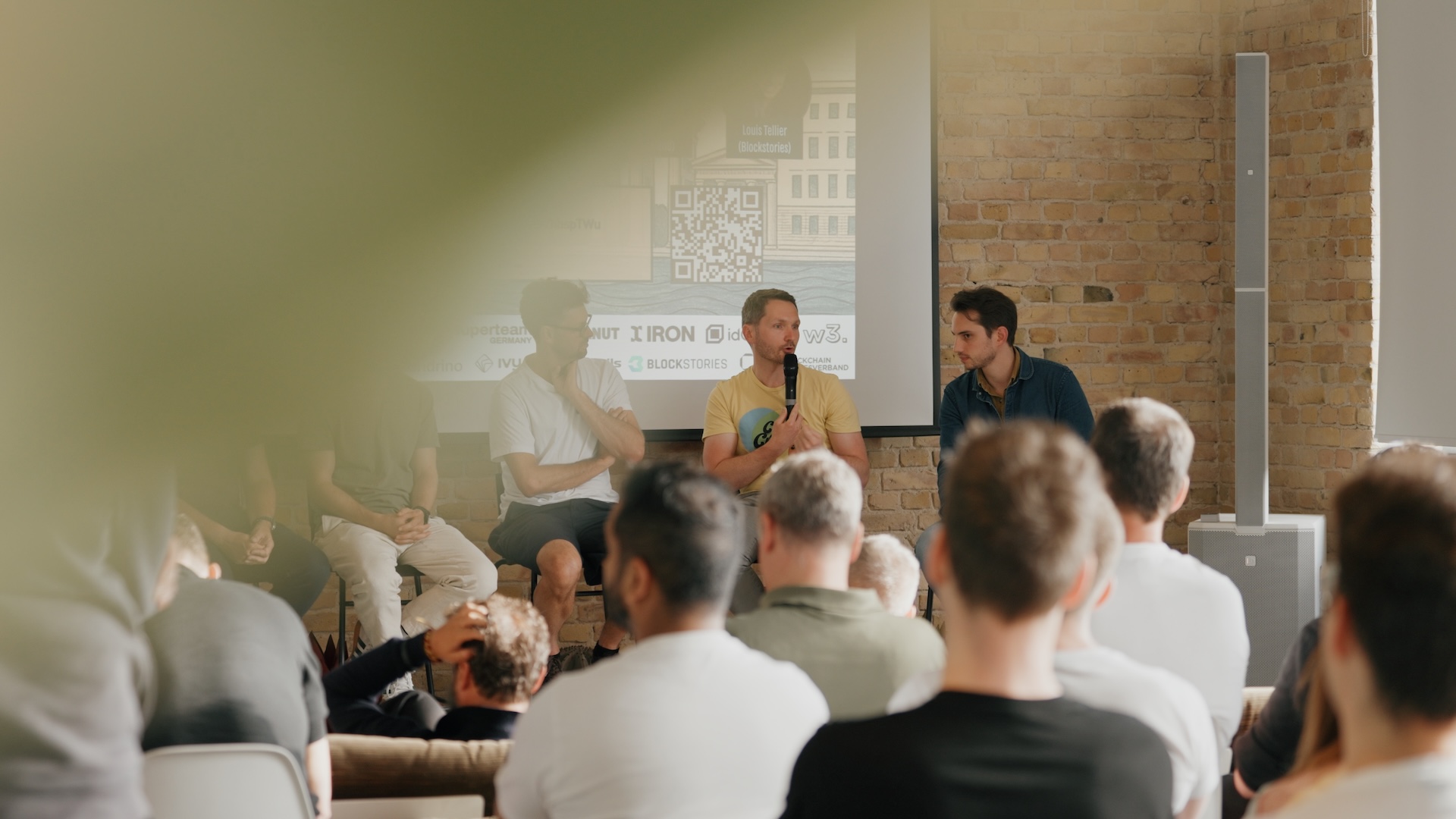 A shot from the Visionary Berlin brand film, capturing a lively panel discussion with Web3 experts in front of an engaged audience at w3.hub.